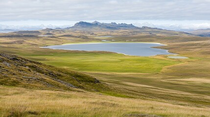 Fototapeta premium Vast Grassland Landscape with Serene Lake and Distant Hills Under Cloudy Sky