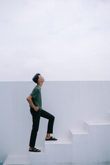 Obraz premium Aspiring young man climbing minimalist white stairs looking ahead