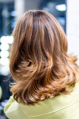 Hair treatments at the hairdressing salon. Female hairdresser's hands brushing and blow drying blonde hair in beauty salon. Hairdresser cutting client's hair with scissors in salon