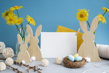 Empty white envelope mock up postcard greeting card copy space with bunny wooden figures and fresh flowers. Easter composition content still life. Christian symbols of spring holiday 