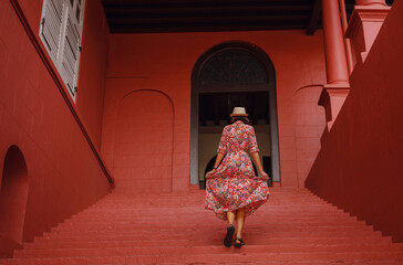 Young woman in ethnic dress and hat exploring the vibrant streets of Malacca, Malaysia. A blend of cultural heritage, colorful architecture, and tropical charm. Perfect travel and lifestyle moments.