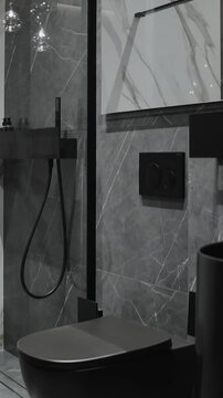  Vertical screen: black toilet in a modern bathroom with gray marble walls