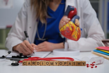 A dedicated medical professional intently studies cardiomyopathy using a detailed heart model and...