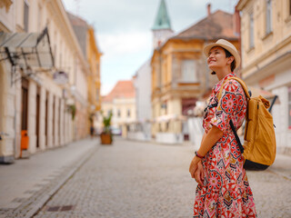 Fototapeta premium Beautiful woman walking of Varazdin streets during summer day in old, historical city center. Tourist exploring the beautiful streets, experiencing relaxed and cultural vibe of this Croatian city.