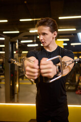 Young Man Intently Working Out at Gym with a Cable Machine for Resistance Training