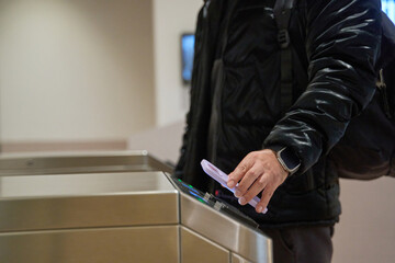 Commuter using smartphone for contactless payment at turnstile