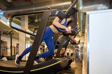 Fitness enthusiast exercising on curved treadmill in gym