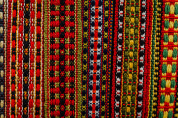 Close-up of a colorful woven textile with intricate geometric patterns in red, green, yellow, and black, showcasing traditional craftsmanship..