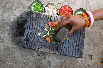 Grinding coriander chutney on stone grinder.
Indian Woman hands grinding fresh coriander leaves...