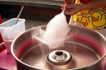 A person is blowing cotton candy out of a machine. The cotton candy is being blown out of a silver bowl