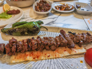 Traditional dish of grilled lamb meat on skewers. Meats lined up on skewers over charcoal fire.