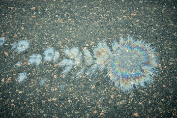 Colorful Oil Spill Pattern on Asphalt Road Creates an Eye-Catching Visual Display During the Day