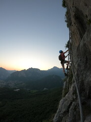 Lecco, Ferrata Gamma 1 - A climber carefully navigates a steep via ferrata at dusk, with a stunning...