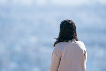 遠くの景色をぼんやりと眺める女性の後ろ姿
