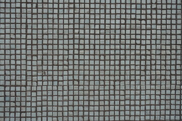 Old and cracked small white rectangular mosaic tiles