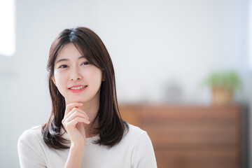 顎に手を当てて考える若いかわいい20代の女性　カメラ目線