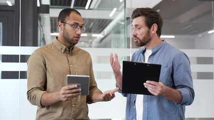 Two angry businessmen arguing intensely standing in modern office, showcasing conflict and emotion during heated business discussion or disagreement. Colleagues fight, disputing, quarreling, problems
