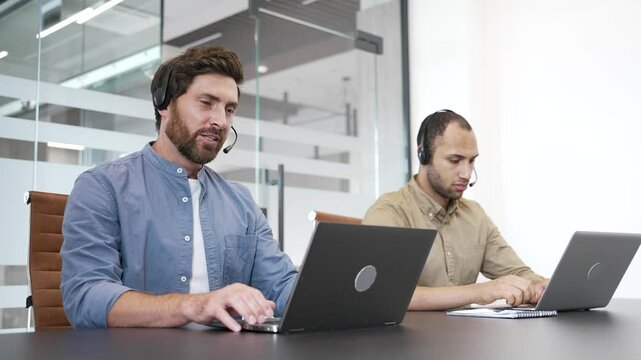 Group of corporate operators working in customer support service on helpline telesale using laptop. A team of call center agents with headsets helping online, speaking on video call in business office