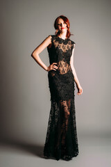 Sexy transparent maxi evening gown in black. Beautiful ginger woman in evening outfit, studio...