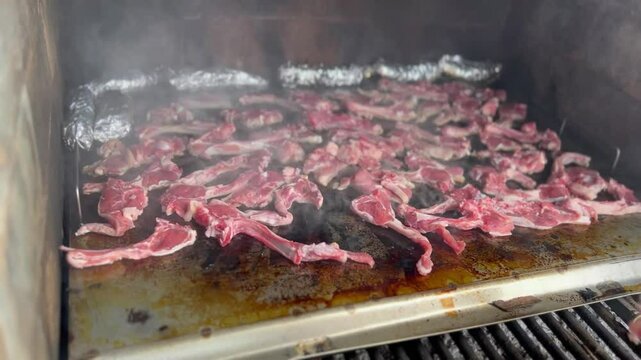 Lamb chops cooking on a smoking grill. Outdoor barbecue.