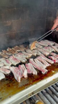Barbeque with raw pancetta. Smoking outdoor grill. Copy space. Vertical video.