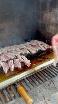 Lamb chops cooking on a smoking grill. Outdoor barbecue. Vertical video.