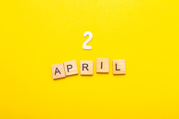 2 April calendar date made by wooden cubes on yellow color background.