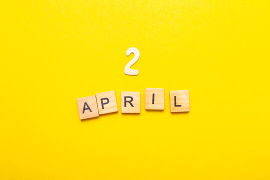 2 April calendar date made by wooden cubes on yellow color background.