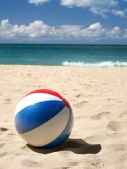 Obraz premium Colorful Beach Ball on Sandy Shore with Ocean and Blue Sky Background