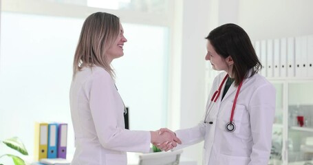 Positive women doctors shake hands for professional greeting in hospital. Female physicians show respect and friendly relations in medical center
