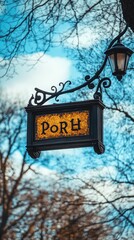 Hanging sign with the letters PORH, lit lamp, trees, and blue sky in the background