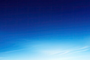 Fototapeta premium Stunning View of a Clear Blue Sky with Subtle Cloud Streaks at Dawn or Dusk