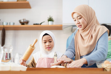 Asian muslim woman and lovely young daughter are preparing and cooking in the kitchen.