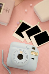 Instant Polaroid photos, a camera for instant printing, and photo albums on a soft pink background,...