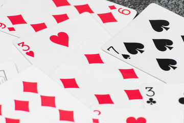 Scattered collection of playing cards, featuring various suits, numbers, and partial card faces. Chaotic arrangement creates a dynamic scene, symbolizing the unpredictability and thrill of card games