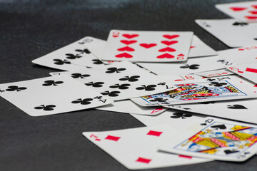 Scattered collection of playing cards, featuring various suits, numbers, and partial card faces. Chaotic arrangement creates a dynamic scene, symbolizing the unpredictability and thrill of card games
