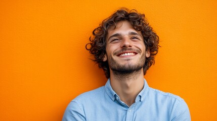 Fototapeta premium Person looks up and smiles; a bright orange wall is the background