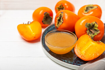 Persimmon jam with slices of ripe persimmon on wooden textured table. Delicious persimmon jam. Marmalade. Healthy sweets. Vegan. Close-up. Space for text. Copy space.