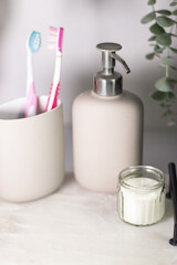 Hygiene items like toothbrushes and liquid hand soap on a marble tray, complemented by greenery in a light, airy interior.