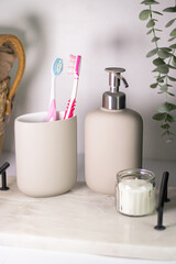 Hygiene items like toothbrushes and liquid hand soap on a marble tray, complemented by greenery in a light, airy interior.