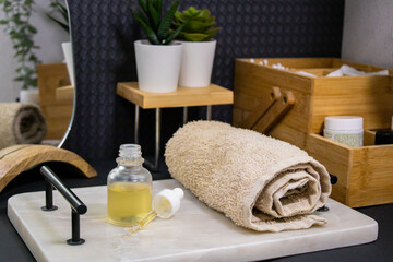 A serum bottle on a marble tray with a soft towel, set against a black background and wooden elements,  face care, hydration, nourishment, and spa treatments, promoting skin health and beauty.