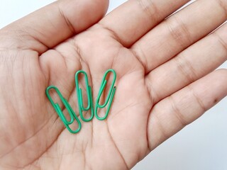  Hand holding three green paper clips