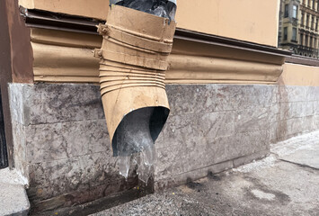 Brown stainless steel pipe with ice inside for draining water from the roof of a house to the ground. Drainage system from the roof of a large building on the exterior wall
