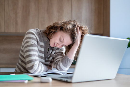 Mental exhausted woman with burnout while remote working at home. Overwhelmed young female feeling stress, frustration, emotional fatigue, unable to focus on tasks. Procrastination, workplace pressure
