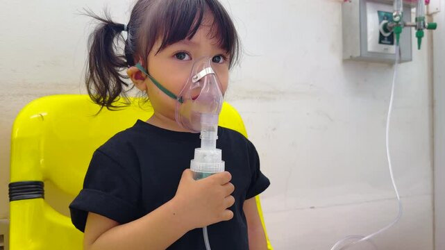 sick toddler baby girl using steam inhaler with nebulizer mask inhalation oneself in hospital
