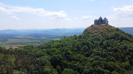 Aerial view of a medieval hilltop Füzér castle and fortress surrounded by lush green forest in...