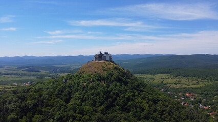 Aerial view of a medieval hilltop F&uuml;z&eacute;r castle and fortress surrounded by lush green forest in the Hungarian countryside. Ancient stronghold, panoramic viewpoint over the rural landscape. Historical.