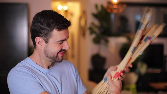 Man holding a traditional strategy game called mikado 