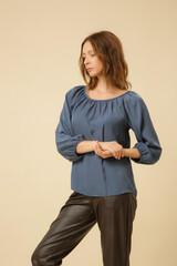 Studio photography of young female model wearing blue blouse and black faux leather trousers....