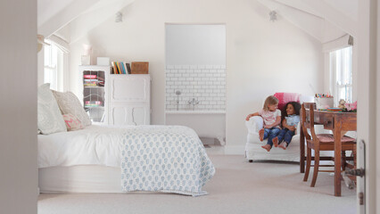 Young Girl With Friend Having Fun Sitting In Chair In Cool Bedroom Together